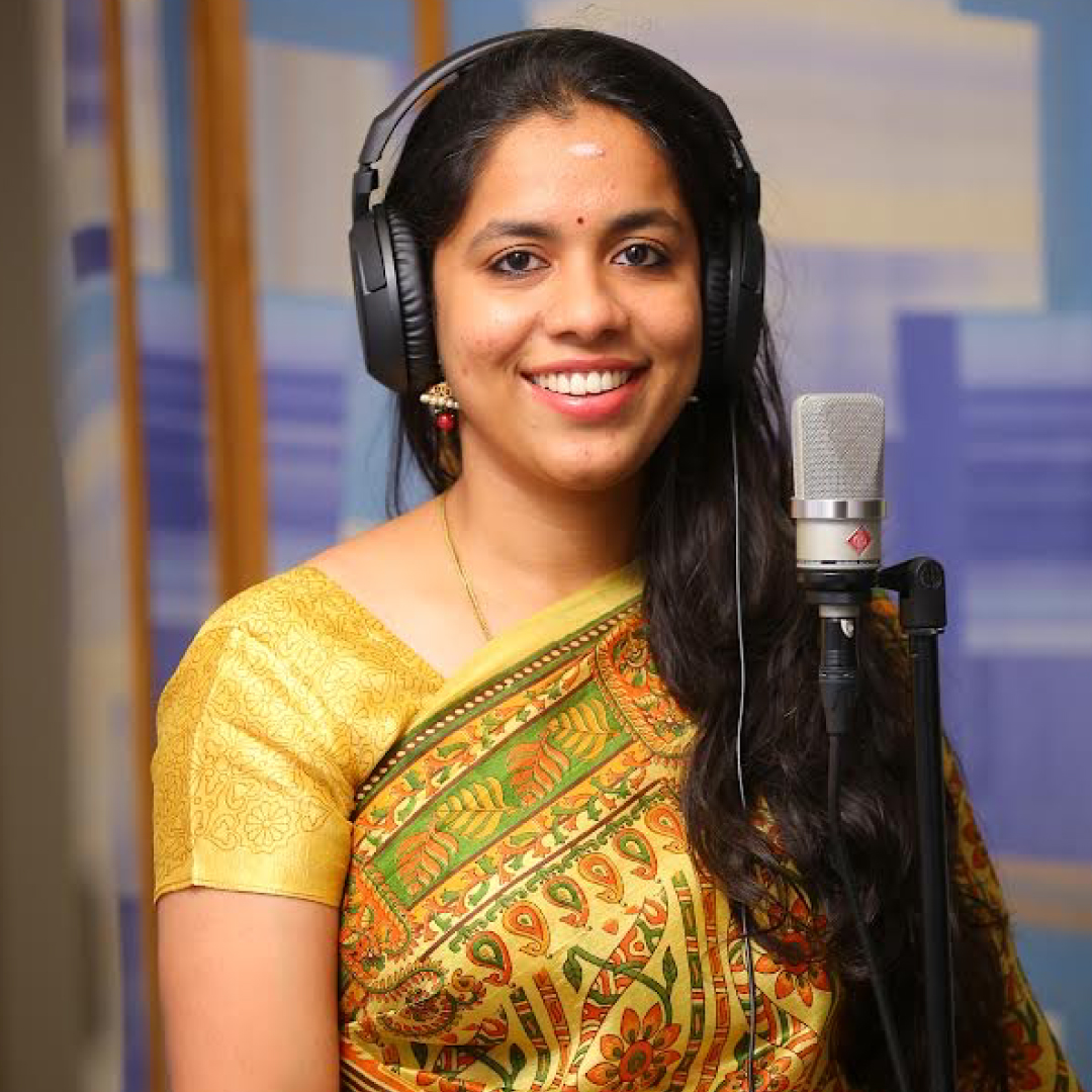 Deepika Arun narrating in the studio, wearing headphones at a condenser microphone
